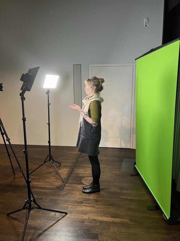 Aufnahme aus der Schulung. Eine Person steht vor einem Green-Screen und moderiert.