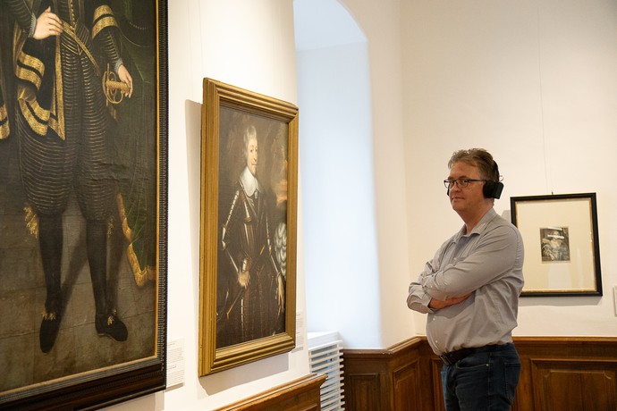 Ein Museumsbesucher mit Kopfhöhrern erhält Informationen zu dem vor ihm liegenden Kunstwerk